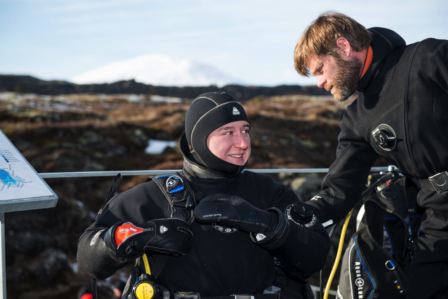 close-up on staff instructors CJ and Mike geared up in drysuit in line for entrance to Silfra dive in the sunny Thingvellir