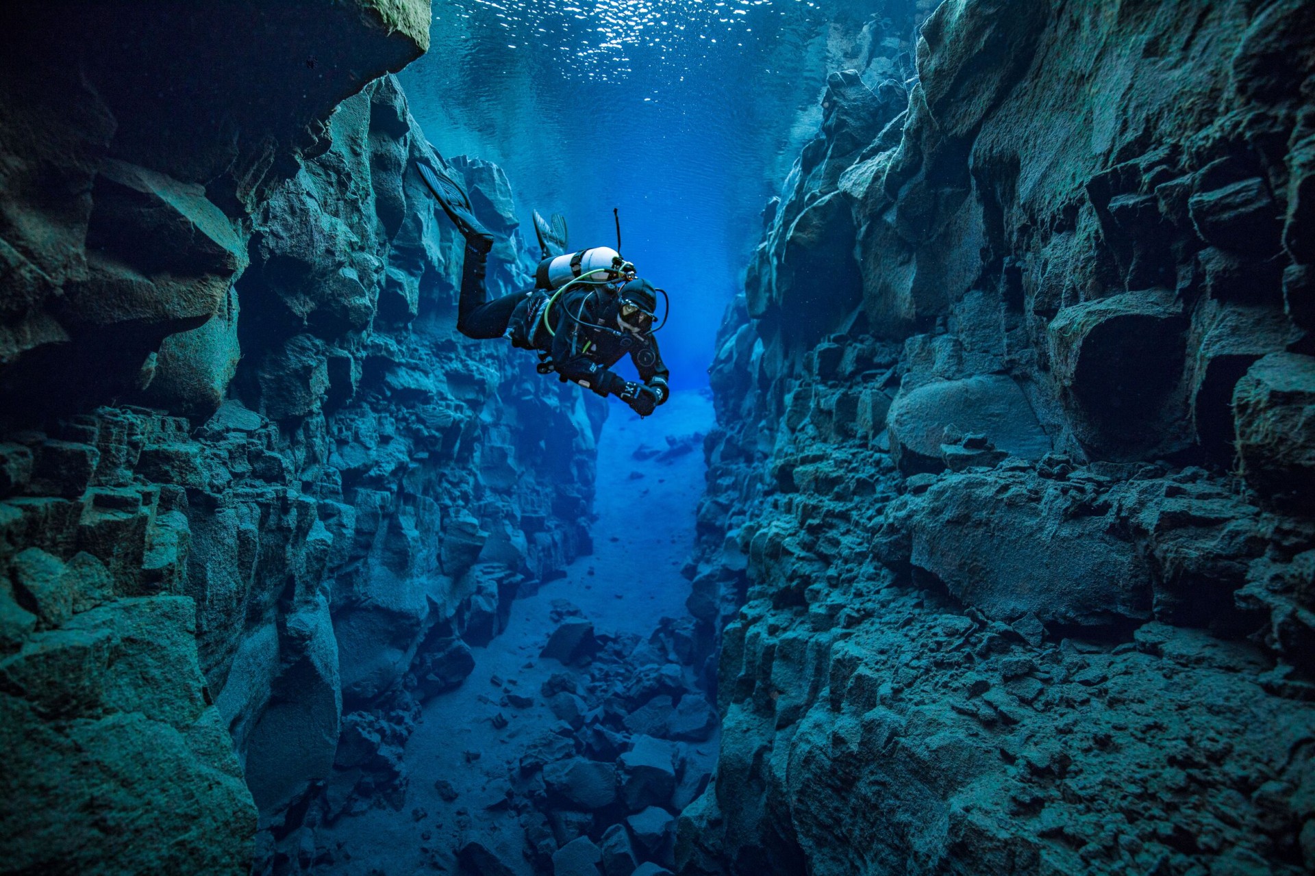 A single diver in full gear in the middle of the crystal clear Silfra fissure at Þingvellir