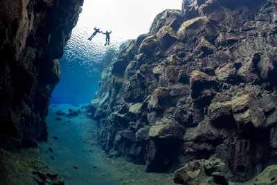 two snorkelers floating in the crystal clear Silfra fissure as seen from below