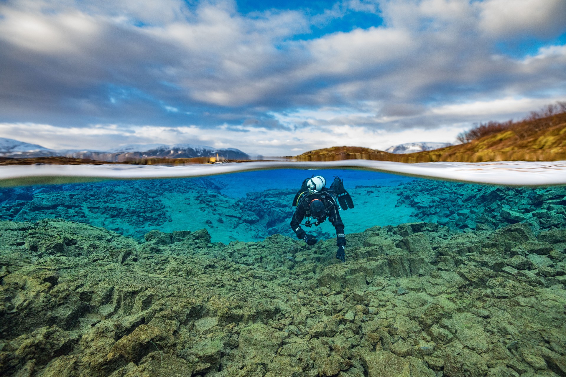 Split view photo of diver in the Silfra lagoon, Thingvellir national park in the background