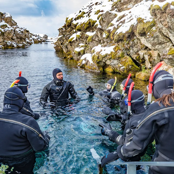 A family of snorkelers entering Silfra with their guide Stefano