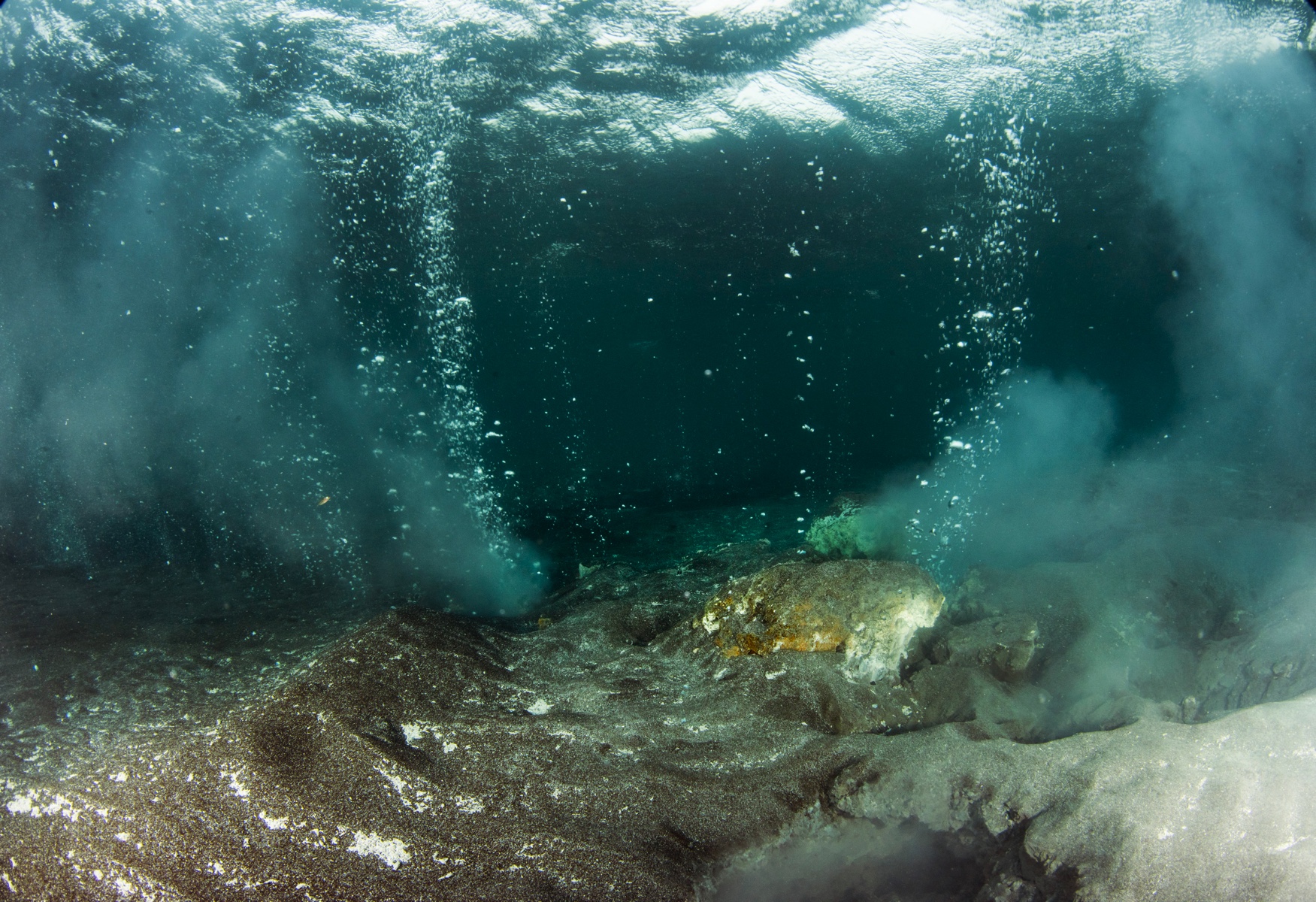 wideangle underwater of Kleifarvatn geothermal cracks with hotwater streams bubbling out of grey sand yellow crusted bottom