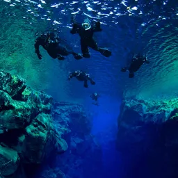 Snorkelers from below floating over Cathedral section in diverse aquamarine colors of Silfra fissure in Thingvellir