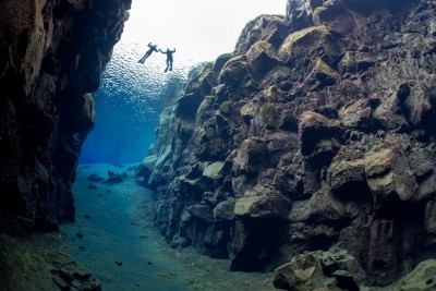 two snorkelers floating in the crystal clear Silfra fissure as seen from below