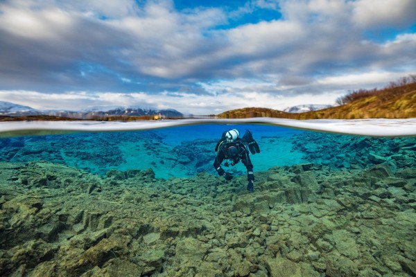 Split view photo of diver in the Silfra lagoon, Thingvellir national park in the background
