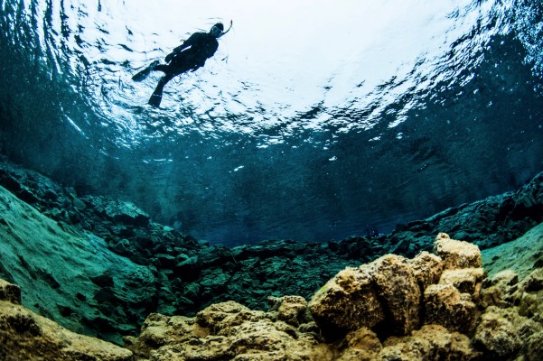 Snorkeler enjoying the midnight sun in Silfra fissure