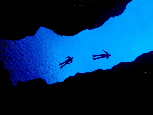 Two snorkelers photographed from the bottom of Silfra cathedral